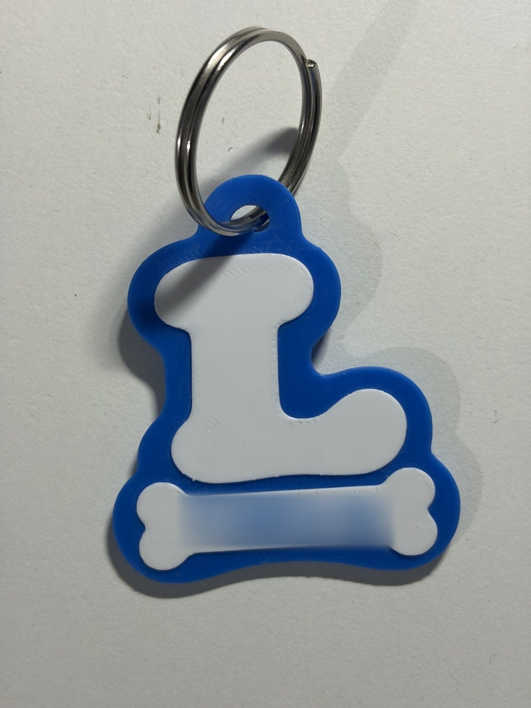 VitalPaws One Tag Gen 6, front: a blue bone-shaped tag with a white letter L