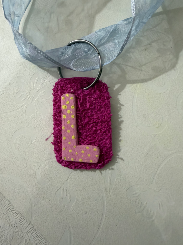 Hand-painted L tag on its ribbon