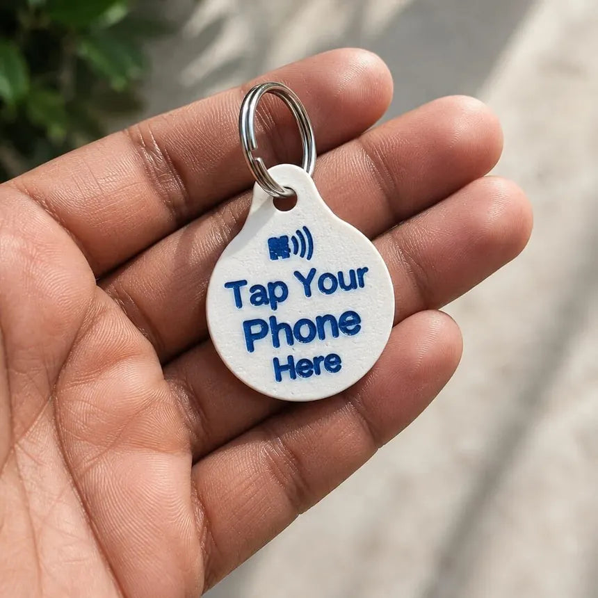 The back of the VitalPaws One Tag Gen 5 in a hand: Tap your phone here, with the NFC mark