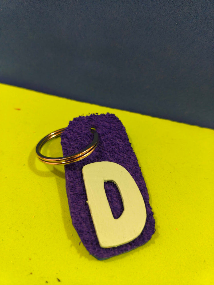 Purple hand-painted geo-tag with letter D on a yellow background